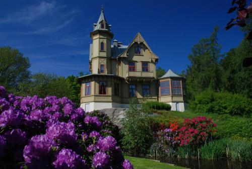 a house on a hill with flowers in front of it at Café Mandeltårtan B&B VillaFloraViola in Ronneby
