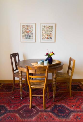 una mesa de madera con sillas y un jarrón de flores. en chambre d'hôte les avettes, en Réméréville