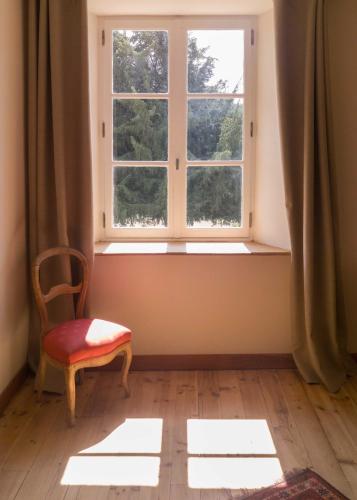 ein Fenster mit einem roten Stuhl in einem Zimmer in der Unterkunft chambre d'hôte les avettes in Réméréville