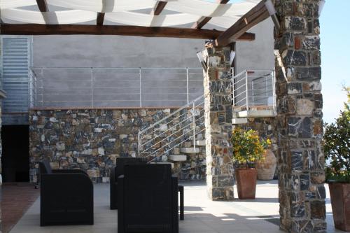 an outdoor patio with a stone wall and a wooden pergola at Villa Serra d'Elci in Ascea