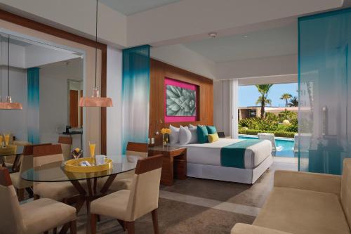 a hotel room with a bed and a dining room at Krystal Grand Los Cabos - All Inclusive in San José del Cabo