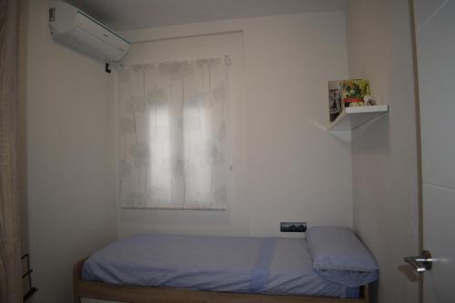 Cette petite chambre comprend un lit et une fenêtre. dans l'établissement Apartamento en el centro histórico, à Cordoue