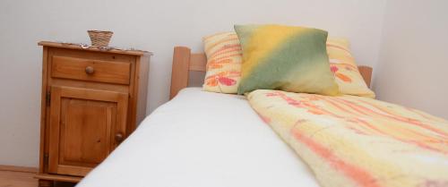 a bed with a pillow and a wooden night stand at Guesthouse Vila Natalija in Gornja Trepča