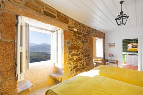 a bedroom with a stone wall and a bed with a window at Quinta do Valdalágea in Peso da Régua