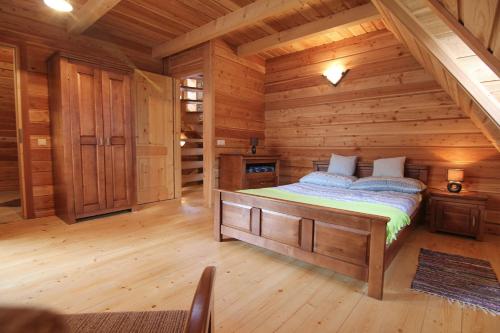 een slaapkamer met een bed in een blokhut bij Domek Koziniec Zakopane in Zakopane