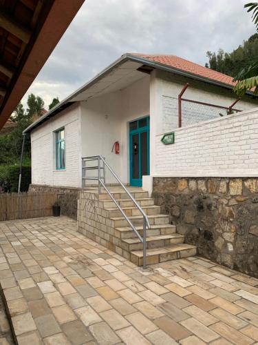 a white house with a blue door and stairs at Palm garden Resort in Gisenyi