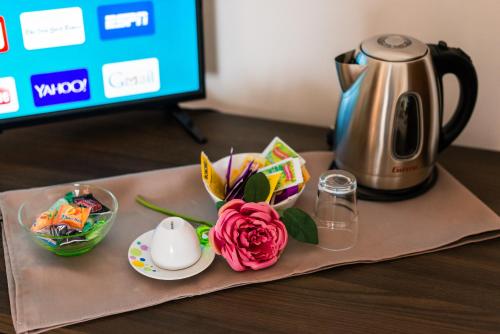 a table with a coffee pot and a pink rose at Le Undici Rose Hotel in Viterbo