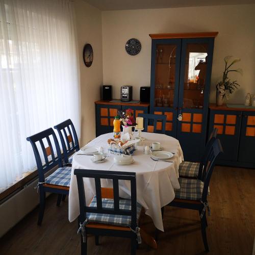 a dining room table with a white table cloth and chairs at Ferienwohnungen und Ferienhaus im Nixenweg in Hohwacht