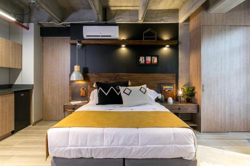 a bedroom with a large bed and a kitchen at Factory Lofts Hotel in Medellín