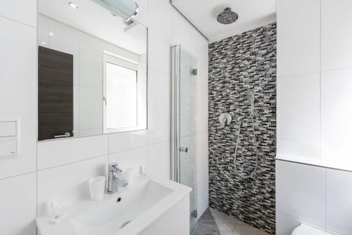 ein weißes Bad mit einem Waschbecken und einer Dusche in der Unterkunft Bürgerhofhotel in Köln