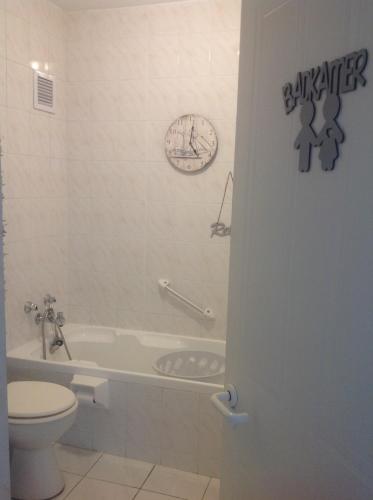 a bathroom with a toilet and a tub and a sink at Beach front property in Strand