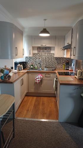a large kitchen with white cabinets and wooden floors at Seaforth Cottage. in Nairn