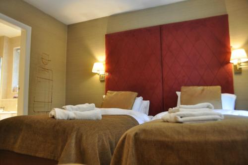 two beds in a hotel room with towels at Tir y Coed Country House in Conwy