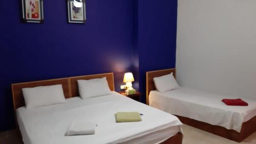2 camas en una habitación con una pared azul en Jordan River Hotel en Amán