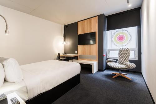 オタワにあるAlt Hotel Ottawa Downtownのベッド、椅子、デスクが備わる客室です。