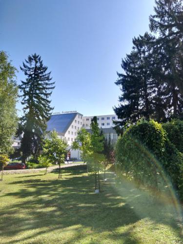 a garden with trees and a building in the background at Hotel Fontana Vrnjačka Banja in Vrnjačka Banja