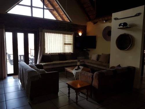 a living room with couches and a large window at Kubu Khaya Mabalingwe in Mabula