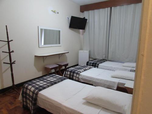 a hotel room with three beds and a television at Pax Hotel , próximo da 25 de Março, Brás, Bom Retiro e República in São Paulo