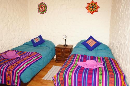 two beds in a room with hats on them at Hostal Mamatierra in San Pedro de Atacama