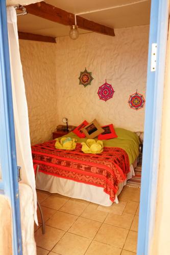 a bedroom with a bed with a red blanket at Hostal Mamatierra in San Pedro de Atacama