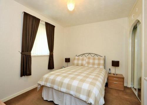 1 dormitorio con 1 cama con manta a cuadros y ventana en WESTEND PROPERTY, en Aberdeen
