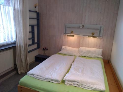 a bedroom with a bed with white sheets and a window at Charmantes Ferienhaus in Nordfriesland in Humptrup