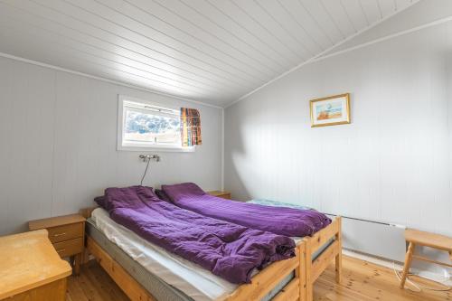 Bett in einem Zimmer mit lila Daunendecke in der Unterkunft Eagle Point Lofoten in Eggum