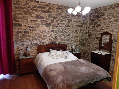 een slaapkamer met een bed en een stenen muur bij A Casa do Ferrador in Vilar