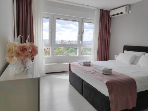 a bedroom with a large bed with a vase of flowers at Penthouse “Sky 16” Studio Apartment in Zagreb