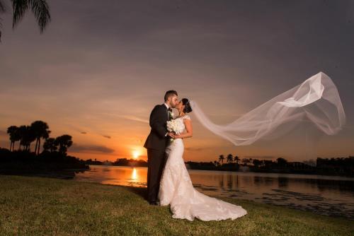 a bride and groom kissing in front of a sunset at PGA National Resort in Palm Beach Gardens