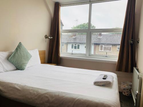 uma cama num quarto com uma grande janela em Albert Guest House em Kingston upon Thames