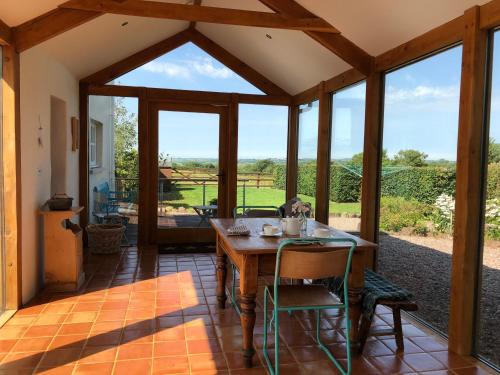 a conservatory with a table and chairs and glass doors at Dan y Graig Barn, Carmarthen in Carmarthen