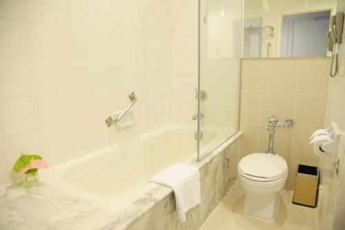 a white bathroom with a tub and a toilet at Royal Princess Larn Luang - SHA Extra Plus in Bangkok
