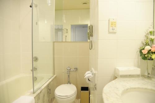 a white bathroom with a toilet and a shower at Royal Princess Larn Luang - SHA Extra Plus in Bangkok