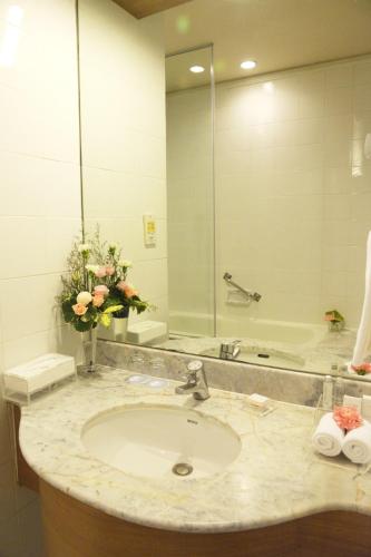 a bathroom with a sink and a large mirror at Royal Princess Larn Luang - SHA Extra Plus in Bangkok
