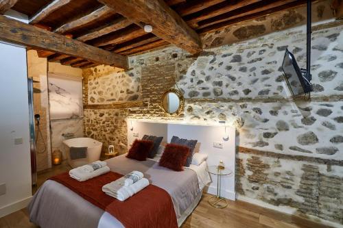 Un dormitorio con una cama grande en una pared de piedra. en Lofts amantes de Toledo -LOFT COBERTIZO, en Toledo