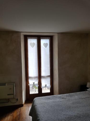 a bedroom with a window with two hearts on it at casa del cirillo in Ornica