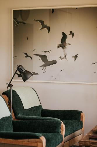 a living room with a green couch and birds on the wall at Emily Moon River Lodge in Plettenberg Bay
