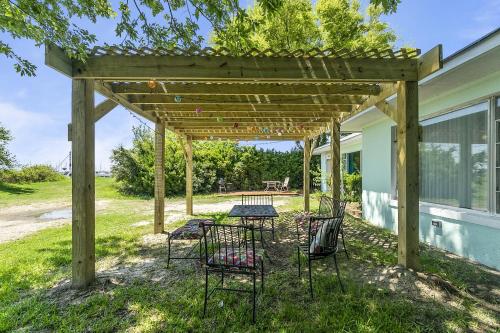 a picnic table under a wooden pergola on a house at Charming Waterfront Cabin Cabin in Norfolk