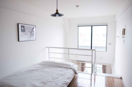 a white bedroom with a bed and a window at MINIMAL SHIMOKITA Stylish Loft or Studio Apt in Tokyo