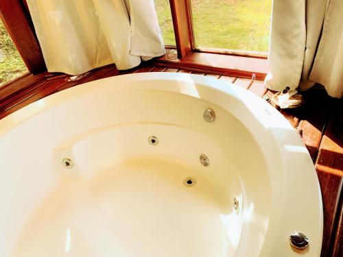 a white bath tub in a room with a window at Pousada Cantinho das Estrelas in Monte Verde