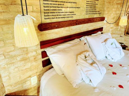 a bed with white sheets and pillows next to a wall at Pousada Cantinho das Estrelas in Monte Verde