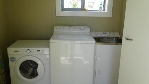 a laundry room with a washing machine and a window at Kumara Historic Cottages in Kumara