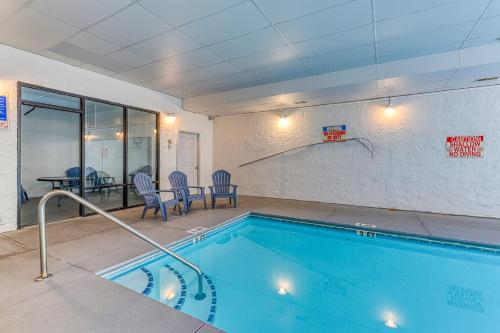 a swimming pool in a room with chairs and a table at Golf View Condo in Pigeon Forge