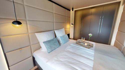 Cette chambre comprend un lit avec des draps blancs et des oreillers bleus. dans l'établissement White Pearl Apartment 2.03, à Timmendorfer Strand