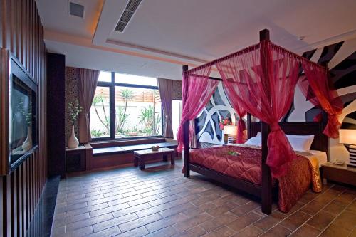 a bedroom with a canopy bed and a window at Chateau Motel & Spa in Kaohsiung