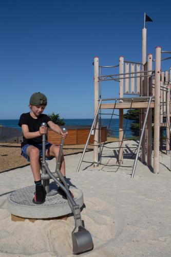 a young boy sitting on a scooter in a playground at BIG4 Apollo Bay Pisces Holiday Park in Apollo Bay