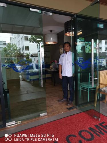 a man in a bow tie standing in a glass doorway at Yeob Bay hotel Ampang in Ampang