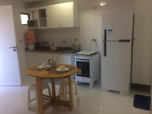 eine kleine Küche mit einem Tisch und einem Kühlschrank in der Unterkunft Beira Mar da Pajuçara in Maceió