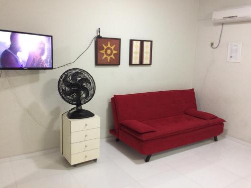 sala de estar con sofá rojo y TV de pantalla plana en Beira Mar da Pajuçara en Maceió